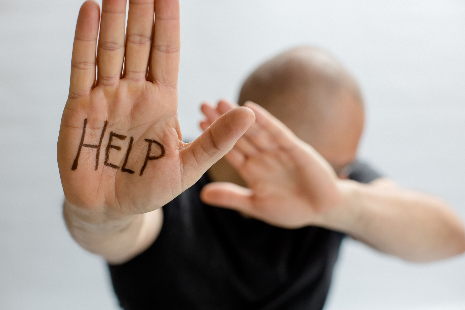 Close up of a male hand with the word "HELP" written on the hand with a pen.